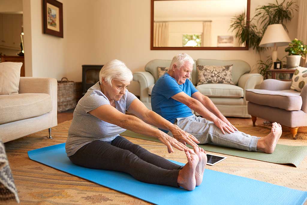 https://www.astongardens.com/wp-content/uploads/2021/11/active-senior-couple-stretching-together-while-doing-yoga-at-home.jpg